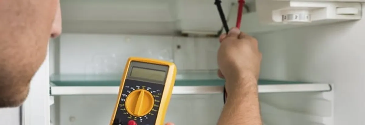 Refrigerator repair technician testing electrical components with a multimeter in Louisville, KY